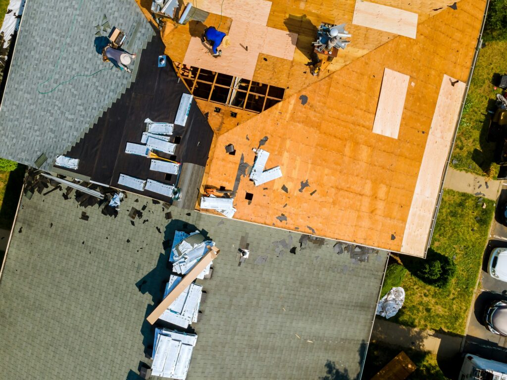 A worker replace shingles on the roof of a home repairing the roof of home